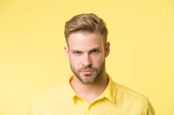 Concetto di mascolinità. L'uomo con la barba o il ragazzo non rasato sembra bello e ben curato. Guy barbuto e attraente si preoccupa per il suo aspetto. Uomo con setole su viso sicuro, fondo giallo — Foto Stock