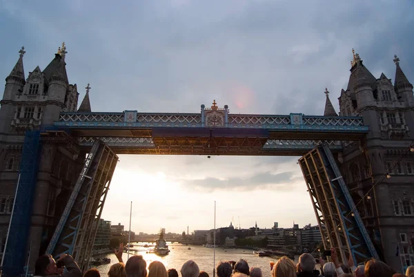 Tower bridge getting opened in London, United Kingdom. People look at bridge over Thames river on grey sky. Architecture and structure concept. Wanderlust and vacation concept — Stock Photo, Image