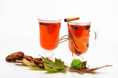 Gözlük mulled şarap veya sonbahar yaprakları ve beyaz arka plan, çerezleri sıcak içecek ile kapatın. Mulled şarap veya sıcak içecek kadehlerin tarçın ile sopa. Sonbahar içecek konsepti