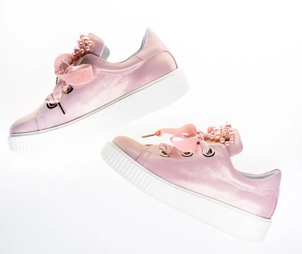 Footwear for girls and women decorated with pearl beads. Trendy sneakers concept. Pair of pale pink female sneakers with velvet ribbons. Cute shoes isolated on white background, top view — Stock Photo, Image
