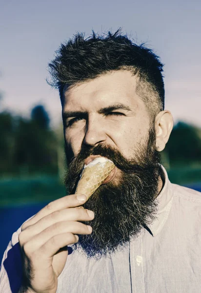 man has ice cream. Man with long beard enjoy ice cream. Sweet tooth concept. Bearded man with ice cream cone