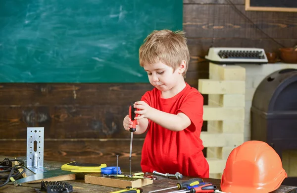 Toddler on busy face plays with screwdriver tool at home in workshop. Kid boy play as handyman. Child cute and adorable playing as builder or repairer, repairing or handcrafting. Childhood concept — Stock Photo, Image