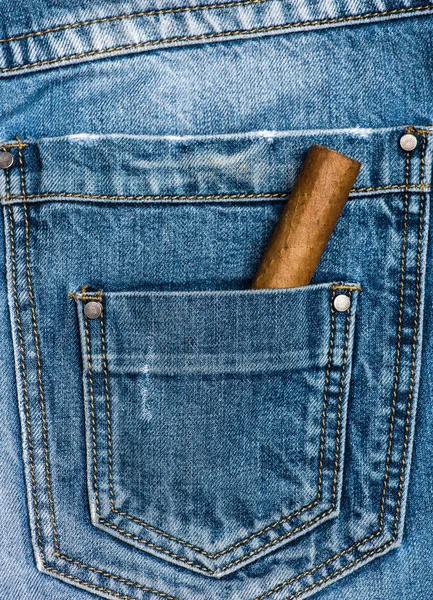 Bolso de jeans com charuto, fundo de ganga. Charuto no bolso de trás de jeans azuis. Conceito de hábitos. Hábito para fumar tabaco de elite — Fotografia de Stock