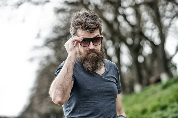 Guy parece legal com óculos de sol elegantes. Homem com barba e bigode usa óculos de sol, fundo desfocado. Hipster no rosto confiante com óculos de sol na moda. Conceito de proteção ocular — Fotografia de Stock