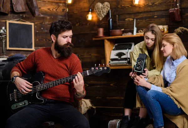 Hombre con barba recortada tocando la guitarra eléctrica. Músico de rock pasar tiempo con la familia en el campo. Hombre barbudo ensayando en casa. Chicas filmando documental sobre instrumentos famosos — Foto de Stock