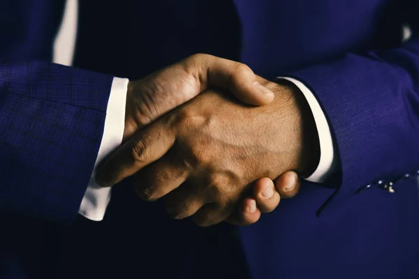 Gli uomini d'affari indossano abiti eleganti. Business deal e concetto di accordo. Mani maschili che stringono forte. Stretta di mano su sfondo grigio chiaro — Foto Stock