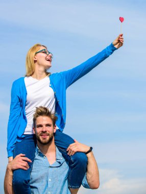 Adam kız arkadaşı omuzlarında, gökyüzü arka plan taşır. Çift mutlu Tarih birlikte eğleniyor. Kadın kalp aşk sopa sembolü üzerinde tutar. İki açık güneşli gün yürüyüş seviyorum. Romantik tarih kavramı