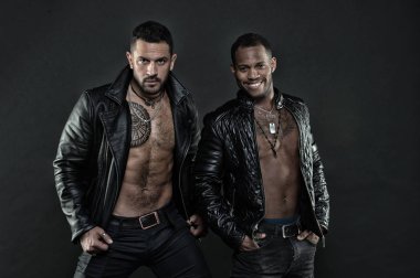 Erkekler gülümseyen yüzler kıl ve dövmeler ile üzerinde. Moda ve stil kavramı. Maço kas torsolar ile deri ceketler, koyu arka plan çekici görünüyorsun. Seksi kas torsolar erkeklerle vahşice bak