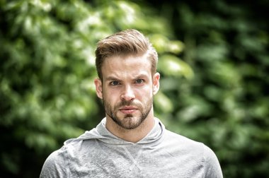 Yakışıklı tarzı. Adam görünümü hakkında çekici umurunda sakallı. Adam defocused ciddi bir yüz, yeşil doğa arka plan, kıl. Metroseksüel kavramı. Adam sakal tıraşsız adam yakışıklı ve serin görünüyor