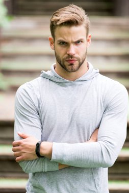 Yakışıklı tarzı. Adam tıraşsız katlanmış silah yakışıklı ve serin görünüyor. Adam görünümü hakkında çekici umurunda sakallı. Adam defocused ciddi bir yüz, kentsel arka plan, kıl. Metroseksüel kavramı