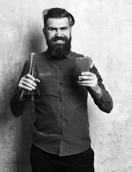 bartender with a cocktail. Brutal hipster holding alcoholic shot and glass tube or flask