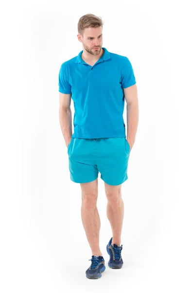 Deportista seguro. Hombre guapo de cuerpo entero en ropa deportiva azul y zapatillas aisladas de fondo blanco. Atleta confiado pone las manos en los bolsillos. Concepto de masculinidad y confianza — Foto de Stock