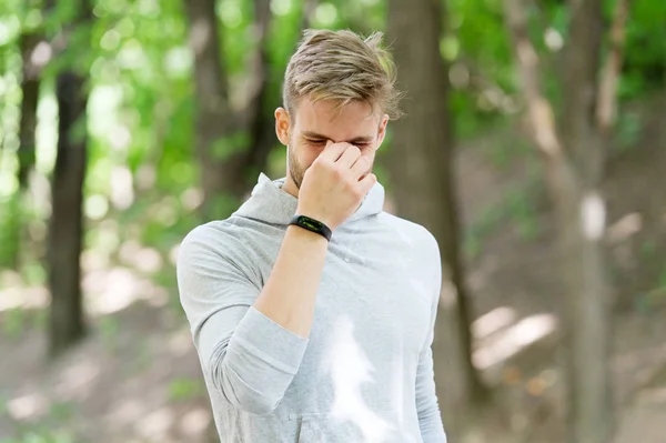 Fájdalom edzés után. A férfi kocogó megáll a parkban fejfájás vagy orrvérzés miatt. Futó lépésszámlálóval a fájdalom miatt fejezte be az edzést. Man runner edzés szabadtéri fájdalmat érez — Stock Fotó