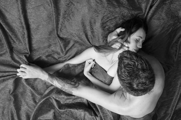 Love, passion and sex concept. Man with tattoos holds pretty sleeping lady in arms — Stock Photo, Image