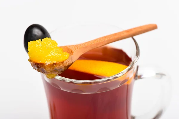 Healing drink concept. Glass with mulled wine with spoon full of honey. Glass with mulled wine or hot tea with grape, cinnamon and honey on white background, close up. Drink with slice of orange — Stock Photo, Image