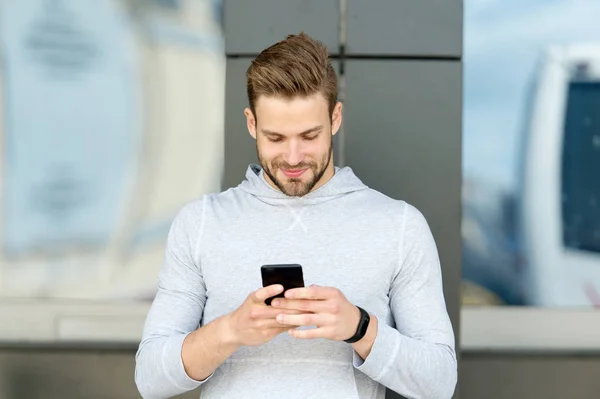 Staying in touch. Man with beard walks with smartphone, urban background. Guy use smartphone to send message stay in touch. Man typing text message smartphone. Send message concept