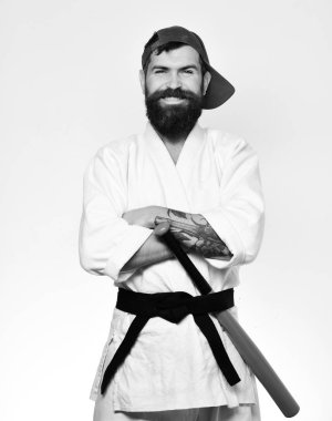 Karate erkek gülümseyen yüzü yeşil beysbol sopası arkasında siyah kuşak koyar. Beyaz kimono ve yeşil kap sakallı