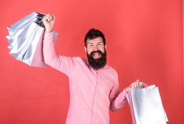 Pembe gömlekli gümüş çanta tutarak uzun sakallı hippi. Sakallı adam neşeli yüzü kırmızı artalanları üzerinde izole kavramı alışveriş. Mutlu adam şık sakal ve bıyık pazarlık ile memnun