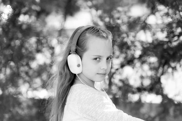 Дитина насолоджується музикою в навушниках на відкритому повітрі. Маленька дівчинка слухає музику в літньому парку. Модна дитина і сучасні технології. Звук мелодії та mp3. Літні канікули і веселощі — стокове фото