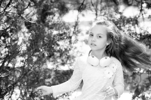 Kinder tanzen zu Musik im Sommerpark. kleine Mädchen genießen Musik im Freien mit Kopfhörern. Kindertänzerin mit langen fliegenden Haaren. Melodieklang und mp3. Sommerspaß und -freude — Stockfoto