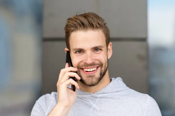 Estaba esperando tu llamada. Barba de hombre con smartphone, fondo urbano. Concepto de comunicación. Hombre con barba feliz sonriente cara hablar smartphone. Chico alegre respuesta llamada en el teléfono inteligente — Foto de Stock