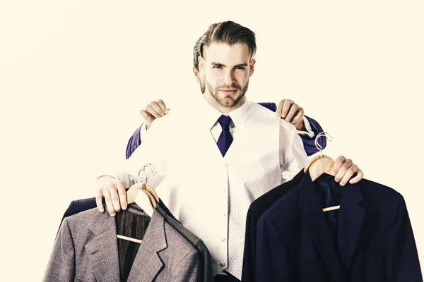 Businessman with serious face buys luxury jackets. Businessman chooses outfit with hands of assistant behind him — Stock Photo, Image