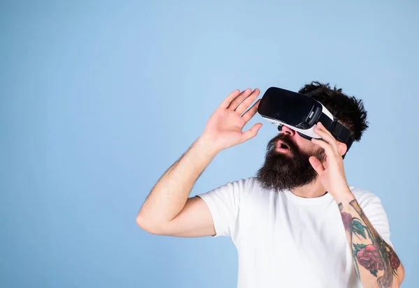 Mann mit langem Bart und Schutzbrille amüsiert sich über neue multidimensionale Erfahrungen. Hipster mit trendigem Bart testet Virtual-Reality-Headset isoliert auf blauem Hintergrund. bärtiger Mann prüft neues Gerät — Stockfoto