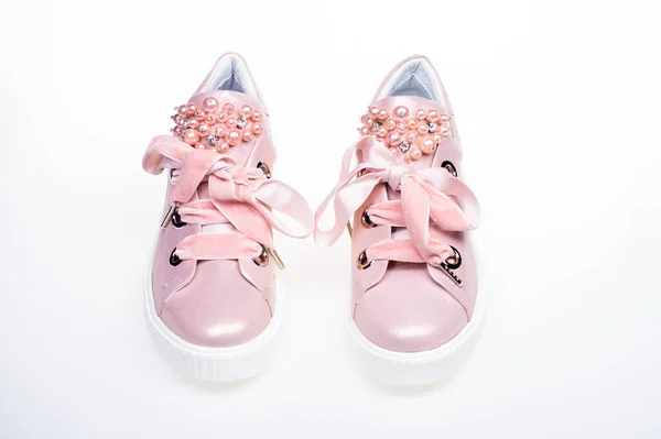 Glamorous sneakers concept. Pair of pale pink female sneakers with velvet ribbons. Cute shoes isolated on white background. Footwear for girls and women decorated with pearl beads — Stock Photo, Image