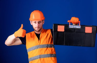 İşçi, repairer, tamirci, Oluşturucu emin yüz taşıyan araç omuz üzerinde. Onarım istişare kavramı. Kask, kask içinde adam araç kutusu tutar ve yukarı hareketi, mavi arka plan gösterir