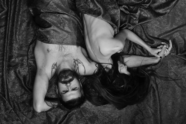 Coppia innamorata su lenzuola a motivi rossi. Mattinata perfetta e concetto di sesso. Uomo e donna con corpi semi coperti si trovano in camera da letto . — Foto Stock