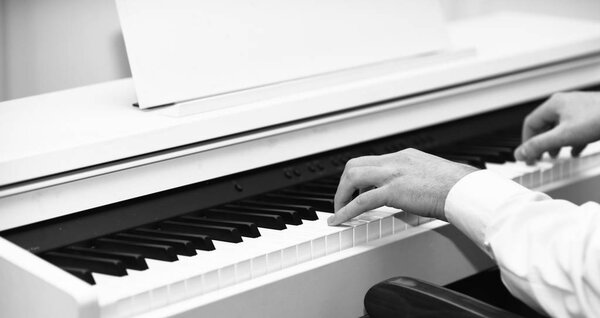 Live music concept. Music performers hands with white cuffs playing piano.