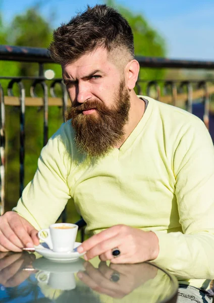 Skäggig man med espressokopp, drycker kaffe. Fika koncept. Mannen med skägg och mustasch på strikt ansikte, staket av terrass på bakgrund, oskärpa. Man med långt skägg ser strikt och allvarliga — Stockfoto