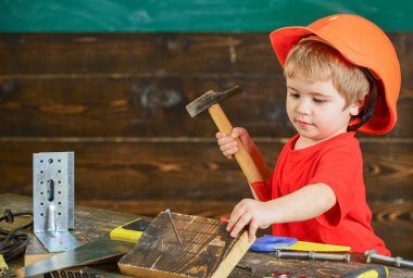 Yürümeye başlayan çocuk meşgul yüzündeki çekiç aracı evde atölye ile oynuyor. Kask Oluşturucu veya repairer, onarımı veya handcrafting olarak oynayan sevimli çocuk. Çocuk Çocuk tamirci oynamak. Handcrafting kavramı