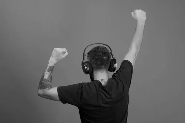 Man holds hands up dancing on blue background. Relax and music concept. Dj with scorpio tattoo wears headphones — Stock Photo, Image