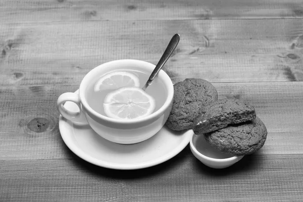 Zoete bakkerij en theetijd. Cookies in de buurt van thee op grijze houten achtergrond. — Stockfoto