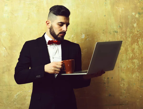 project manager with serious face puts coffee on laptop