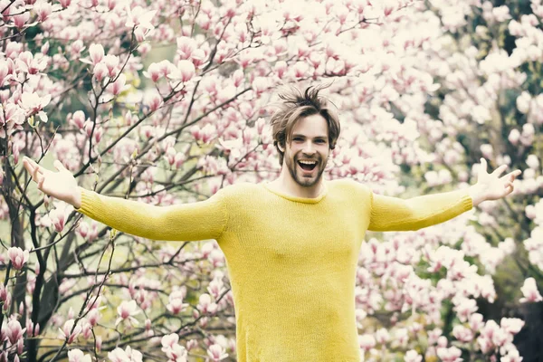 New life and optimism. Guy in yellow sweater with open hands on floral background