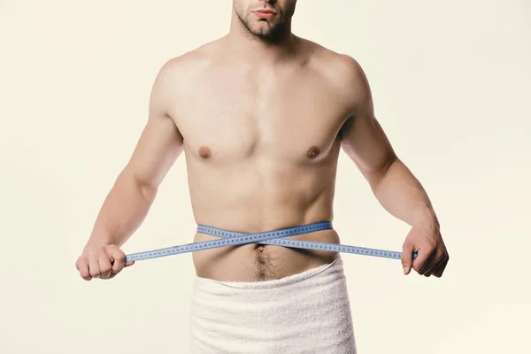 Tipo con toalla y regla flexible aislado sobre fondo blanco. Concepto de medición y estilo de vida deportivo. Hombre con cinta métrica azul — Foto de Stock