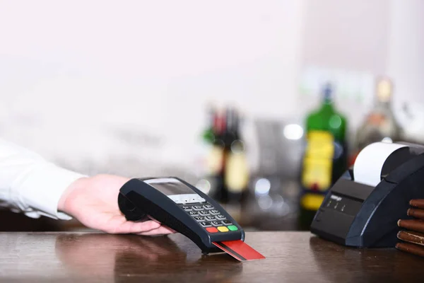 Caixa mão detém leitor de cartão de crédito em fundo desfocado luz . — Fotografia de Stock