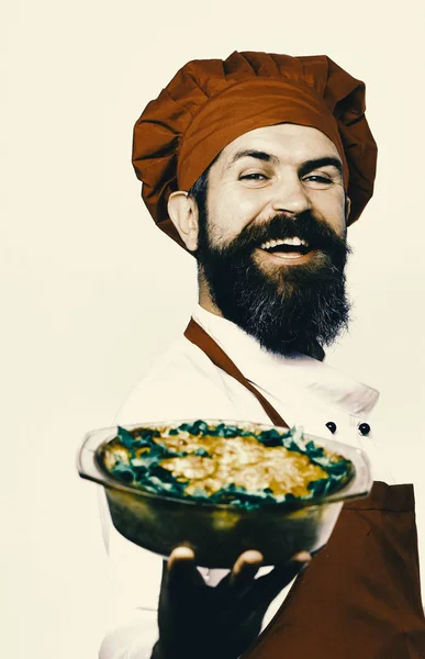 Matlagning och vegetarisk kost koncept. Mannen med skägg isolerad på vit bakgrund. Kock med glada ansikte i Bourgogne enhetliga innehar bakad maträtt — Stockfoto