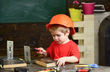 Turuncu baret veya kask, çalışma odası arka plan çocuk evlat. Çocuk Oluşturucusu'nu veya repairer oynamak, aletlerle çalışırız. Gelecekteki kariyer mimarisi veya bina hakkında rüya çocuk. Çocukluk kavramı