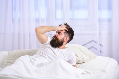 Arka plan üzerinde yatak uyanık, beyaz perde döşeme tişörtlü adam. Akşamdan kalma kavramı. Sakal ve bıyık maço çağrı uyanık uyuya kalmışım. Adam sabah uyanma hayal kırıklığına acı yüzü