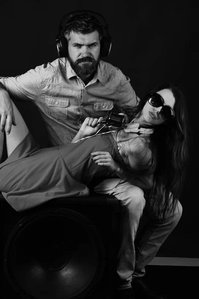 Music fans listen to music. Man with beard and serious face holds girl on boombox on black background. Party and music concept. Couple in love wears headphones