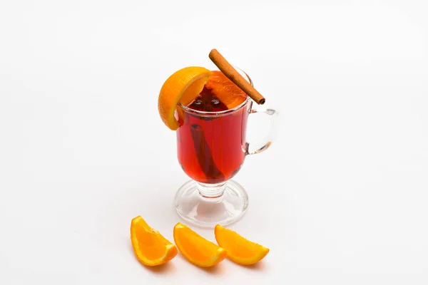 Vino caliente cerca de rebanadas de naranja. Concepto de cóctel y bar. Copa con vino caliente o sidra caliente cerca de fruta naranja y rebanadas sobre fondo blanco. Bebida o bebida con naranja y canela —  Fotos de Stock