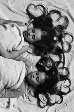 Hareketsiz yüzleri ve kalp şeklinde saç yatakta çocuklarla