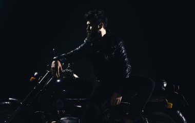 Vahşet ve eril kavramı. Maço, vahşi Motorcu deri ceketli gece zaman motosiklet dur. Sakallı, bisikletçinin yalın motorlu bisiklet karanlıkta siyah arka plan üzerinde deri ceketli adam