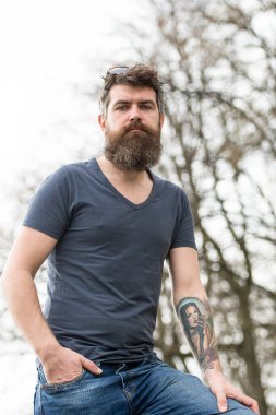 Sakal ve bıyık sıkı yüzündeki defocused arka plan, ağaçta olan adam. Casual kıyafet açık poz içinde sakallı adam. Uzun sakallı adam şık ve kendinden emin görünüyor. Berber ve stil kavramı