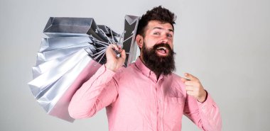 Satış ve indirim kavramı. İleriye dönük bir alışveriş satış sezonu üzerinde adam. Mutlu yüz hipster Alışverişkoliğin bağımlısı. Sakal ve bıyık taşır grup alışveriş torbaları, gri arka plan ile adam