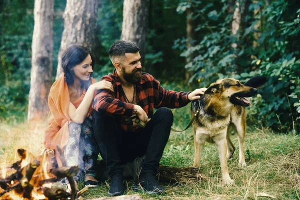 Mujer y hombre de vacaciones, disfrutar de la naturaleza. Pareja enamorada, joven feliz familia pasar el ocio con el perro . — Foto de Stock