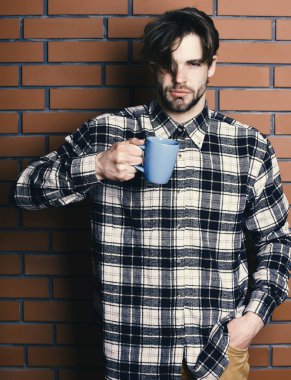 Duvarda fincanı tutan yakışıklı adam.
